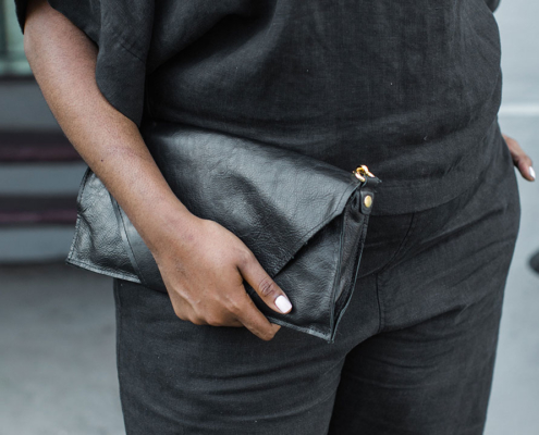 Photo of a woman holding a black fold-over clutch from Bevy goods