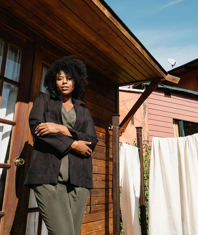 Woman standing in front of a wooden house wearing the sedona chore jacket in black.