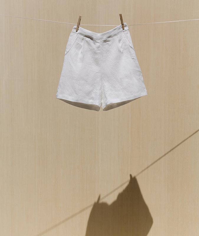Photo of the Isamu short in ivory linen hanging on a clothesline