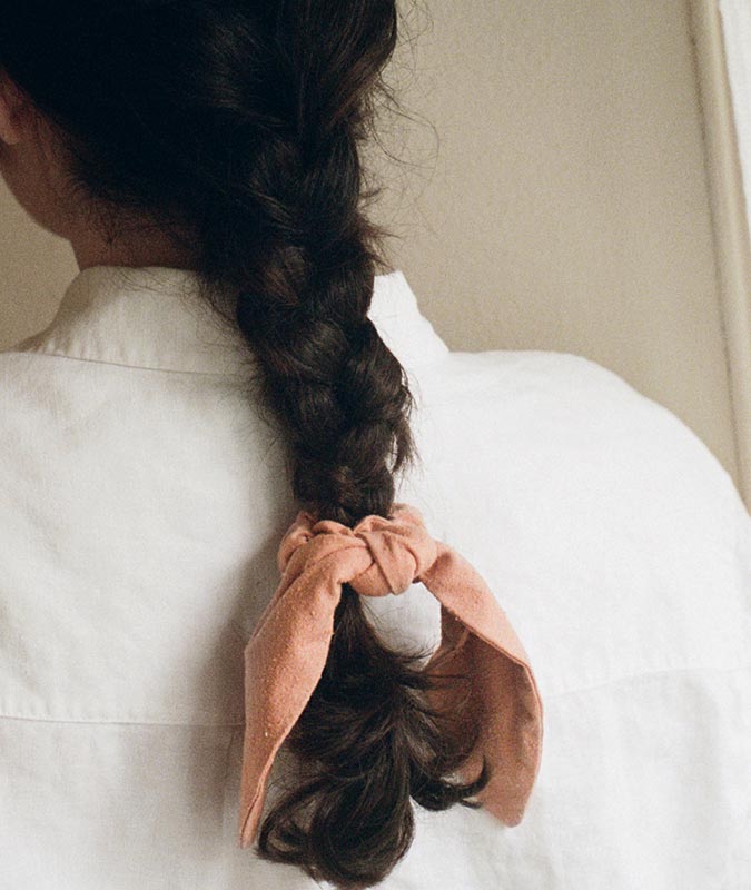 photo of the knotted scrunchie with tie in dusty rose at the end of a low braided ponytail