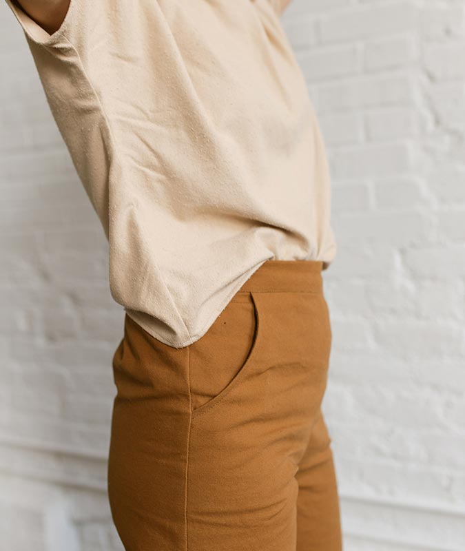 close up of a woman wearing the natural, cream colored krissy tee tucked into natural fiber orange pants