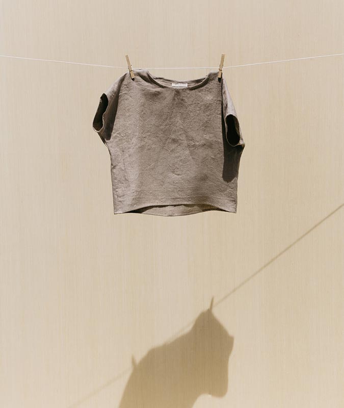 The Krissy Tee in flax linen hanging from a clothesline.