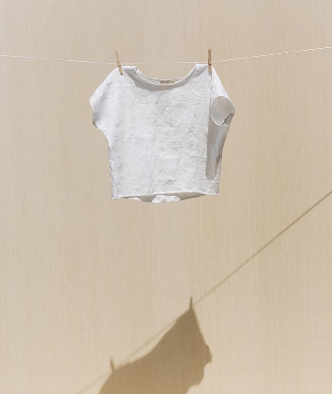 The Krissy Tee in ivory linen hanging from a clothesline.
