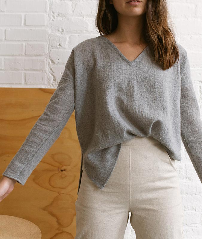 close up photo of a woman wearing the natural fiber, v-neck lucia sweater in light grey
