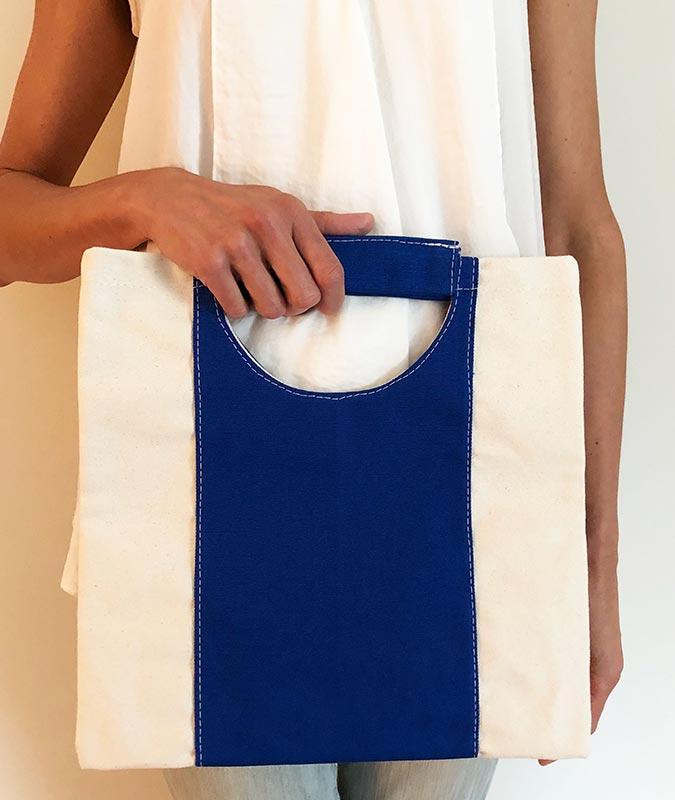 woman holding the bevy union foldover bag in blue.